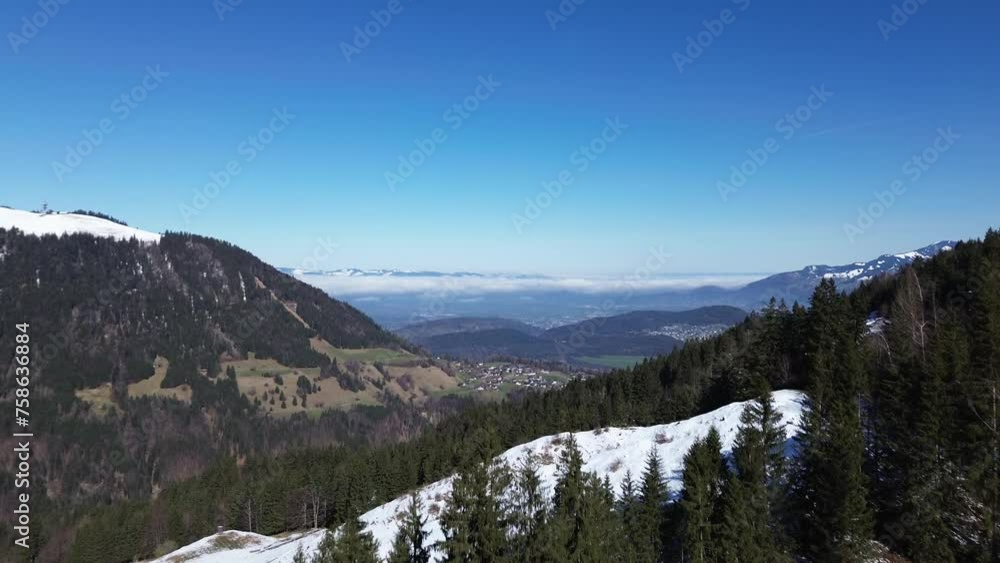 Drone fly along mountain road in winter in austria with amazing view over small towns far away