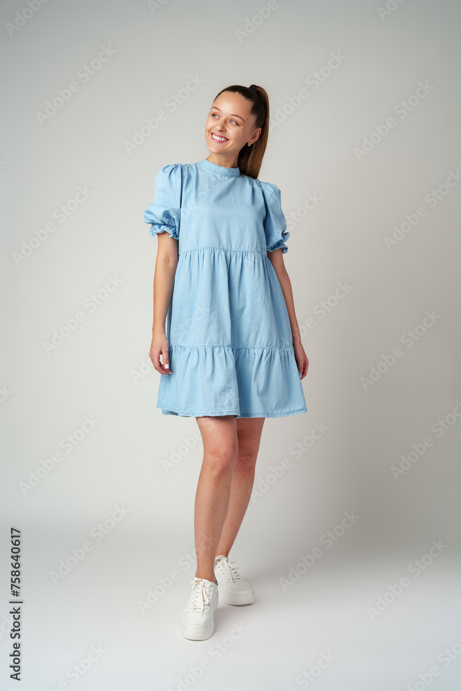 Young happy smiling woman in a light blue dress on a gray background Young happy smiling woman in a light blue dress on a gray background