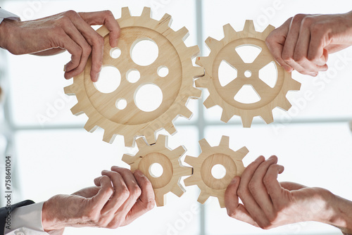 Hands of people office workers business partners making common picture of wooden gears on table, selective focus