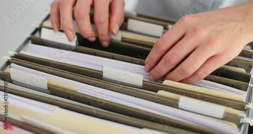 Woman employee sorts through documents in folders from box