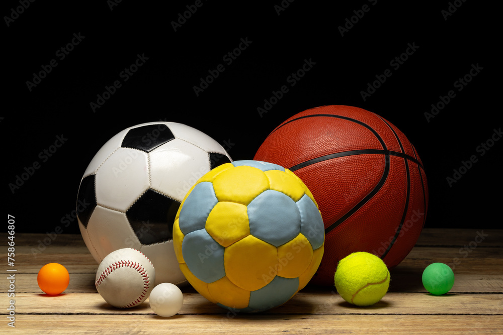 Set of various sport balls on wooden floor on black background