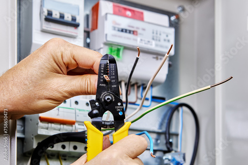 Tool for stripping wires is used when installing an outdoor electrical panel with an electricity meter and circuit breakers.