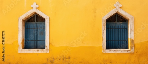 Two ancient windows on a yellow wall without anyone.