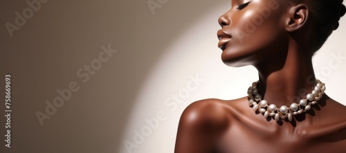 Beautiful ebony woman with pearl necklace on a beige background with copy space. photo