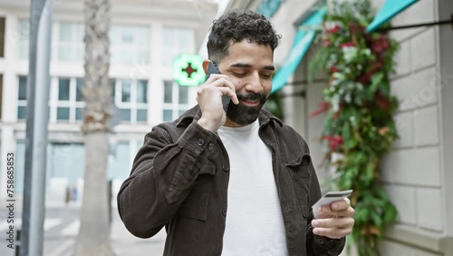Handsome bearded man talking on mobile phone while holding a credit card on a city street. photo