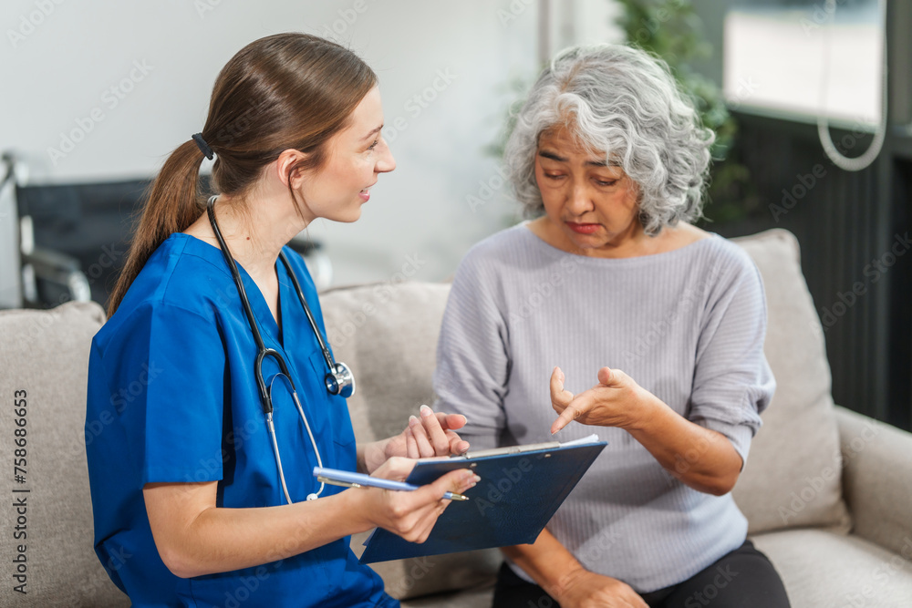 Caucasian teenager female doctor consults with and Asian elderly patient on medical history, discussing headaches, chest pain, coughing, sneezing, stomach pain, and neck pain while seated on a sofa. Caucasian teenager female doctor consults with and Asian elderly patient on medical history, discussing headaches, chest pain, coughing, sneezing, stomach pain, and neck pain while seated on a sofa.
