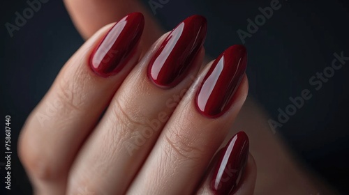 A woman s hand with a beautiful burgundy manicure.