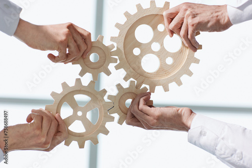 Hands of people office workers business partners making common picture of wooden gears on table