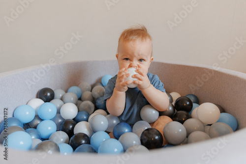 Closeup little boy play in dry pool with colorful balls in living room photo