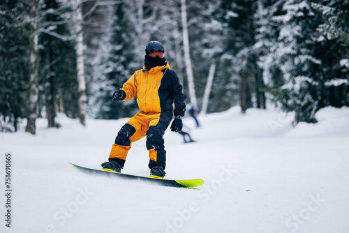 Freeride snowboarding in Sheregesh Ski Resort on background snowy forest. Man snowboarder rides through snow, explosion