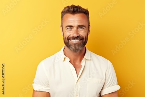 Portrait of a handsome man smiling at the camera over yellow background © Loli
