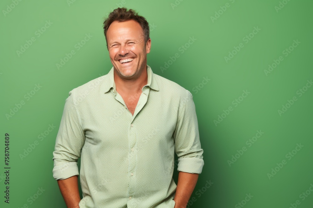 Handsome middle aged man laughing and looking at camera over green background. Handsome middle aged man laughing and looking at camera over green background.