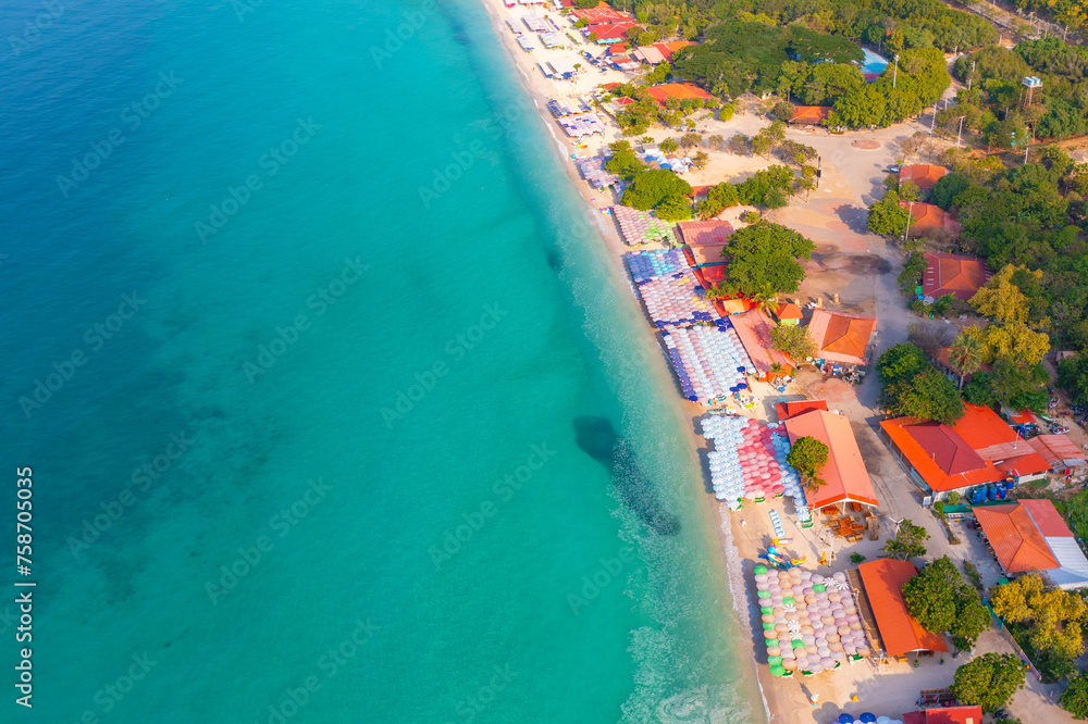Aerial top view colorful umbrellas on sandy beach,empty blue sea summer sunny morning. Resort tropical seascape turquoise water, travel vacation pier, dark spot school of fish.