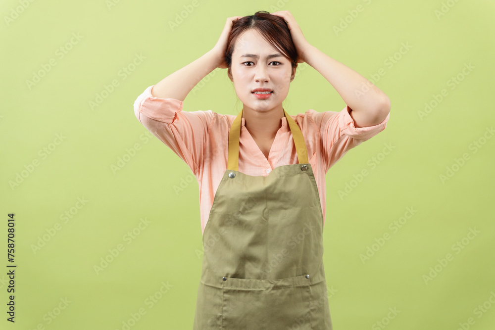 Photo of young Asian female housekeeper on green background