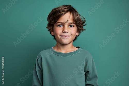 Portrait of a cute little boy looking at camera over green background