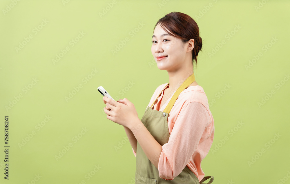 Photo of young Asian female housekeeper on green background Photo of young Asian female housekeeper on green background