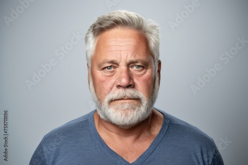 Portrait of a senior man with grey hair and beard on gray background