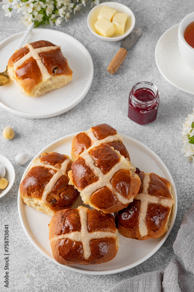 Traditional Easter hot cross buns on a white plate with butter, berry jam and cup of tea. Delicious Easter breakfast. Traditional Easter hot cross buns on a white plate with butter, berry jam and cup of tea. Delicious Easter breakfast.