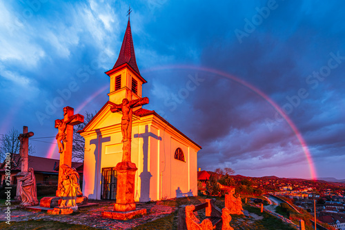 The Chapel of Saint Thomas Becket in Szent Tamas lighten by a strong sunlight with a rainbow behind in rainy clouds in Esztergom, Hungary.