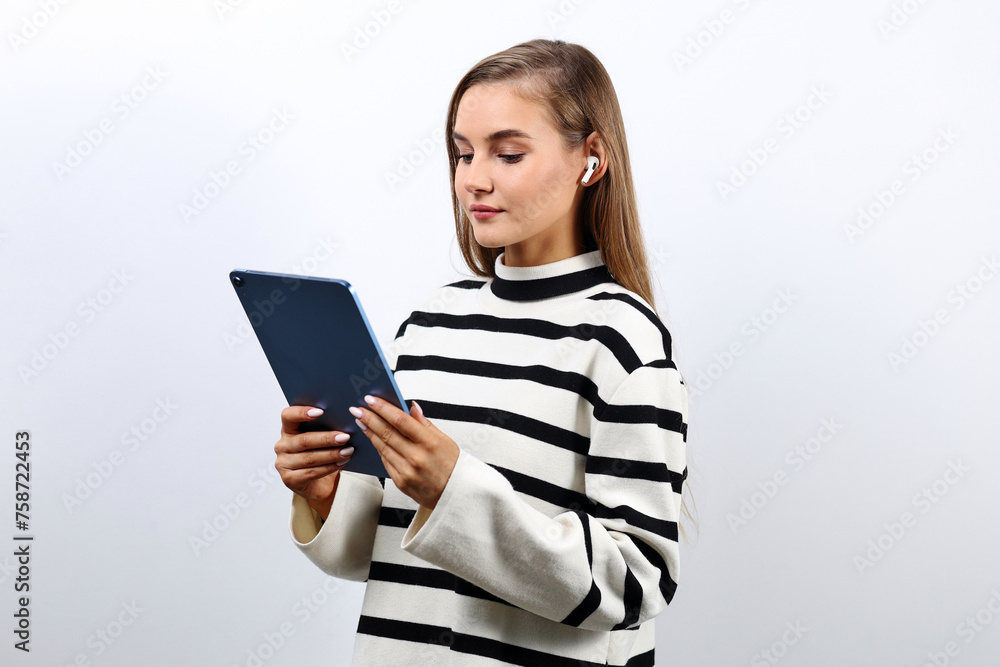 Young pretty student woman in a striped sweater with a tablet on a studio background Young pretty student woman in a striped sweater with a tablet on a studio background