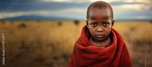 Young Masai boy in red shuka on African savanna photo