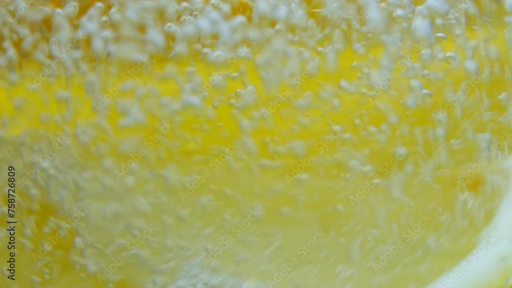 Lemon slices fall into sparkling water. lemonade in a glass, macro. Fruit lemon cocktail close-up texture, healthy sweet drink. Detox drink, summer refreshment concept. The bubbles are bubbling Lemon slices fall into sparkling water. lemonade in a glass, macro. Fruit lemon cocktail close-up texture, healthy sweet drink. Detox drink, summer refreshment concept. The bubbles are bubbling