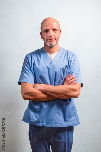 Portrait of a physiotherapist in light blue gown looking at camera in studio. © karrastock