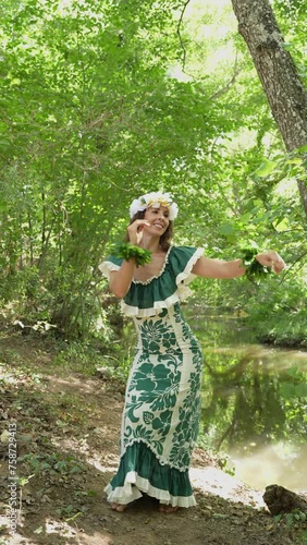 Woman dancing with her hands and body performing traditional dance from Tahiti and the Pacific Islands in a green and tropical forest.