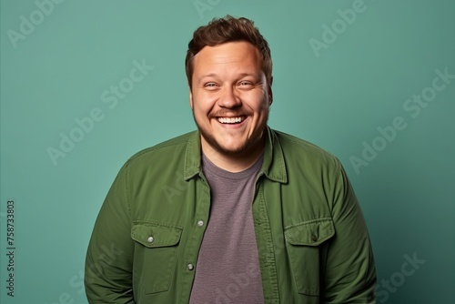 Portrait of a happy young man laughing against turquoise background
