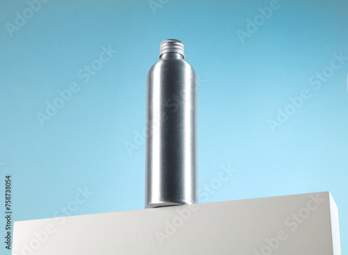 Metallic silver bottle with screw cap without label. Medicine and cosmetics. On white base with blue background (ID: 758738054)