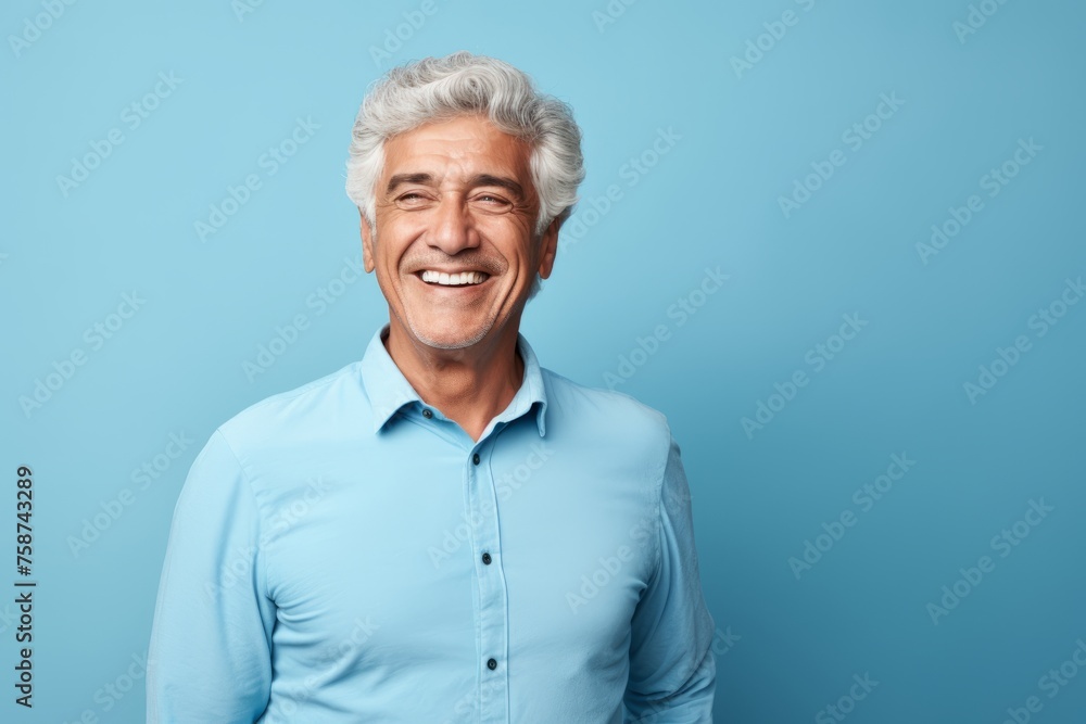 Portrait of smiling senior man with grey hair and blue shirt on blue background Portrait of smiling senior man with grey hair and blue shirt on blue background