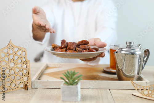 Muslim man holding a plate of dates fruit to break fasting during ramadan