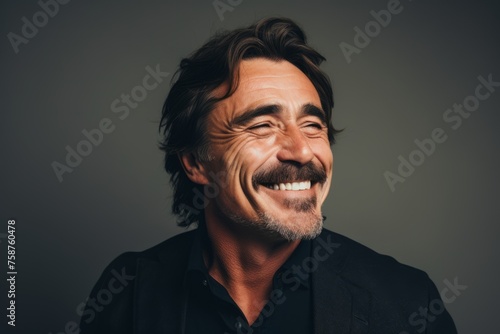 Handsome mature man laughing and looking at camera on grey background © Loli