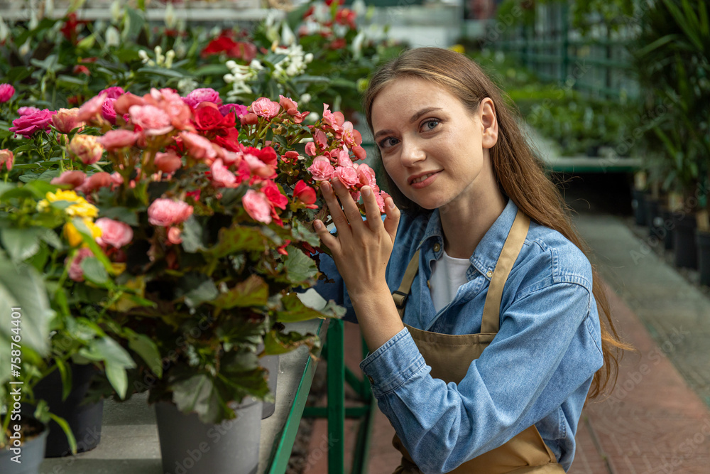 A young girl takes care of indoor plants in a greenhouse.