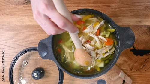 stirring a pot of soup with vegetable and chiken meat. top view. Healthy meal for dinner. hot and cozy soup for dinner at home