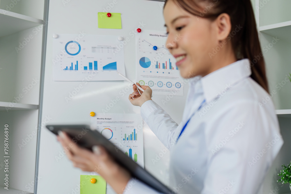 woman standing in front of whiteboard with tablet for present Profit analysis of company while meeting woman standing in front of whiteboard with tablet for present Profit analysis of company while meeting