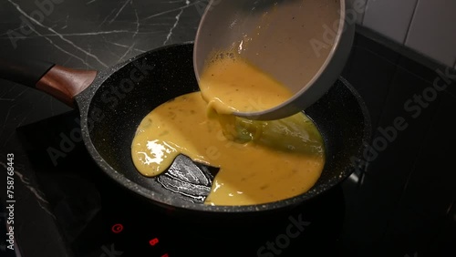 Pouring beaten eggs on hot frying pan with oil. Cooking Breakfast. close up
