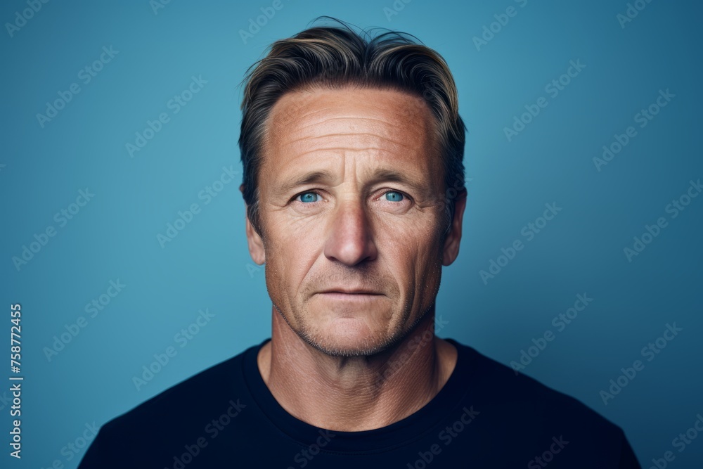 Portrait of a middle aged man looking at the camera on a blue background Portrait of a middle aged man looking at the camera on a blue background