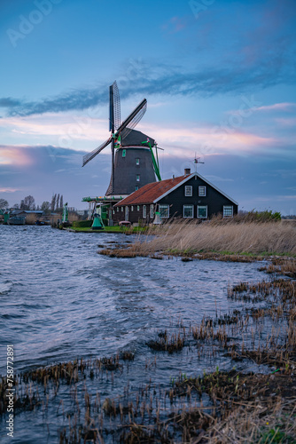 Beautiful Dutch landscape of Zaanse Schans village in Netherlands in spring time. Ancient windmills at the water's edge against a blue sky at dusk