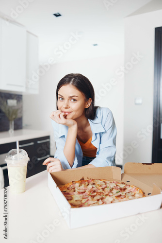 Young woman enjoying a delicious pizza and refreshing drink at a table in a cozy restaurant