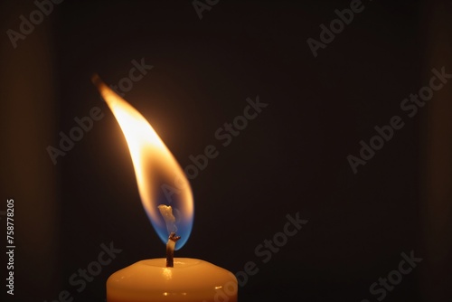 Nahaufnahme einer Kerzenflamme in einem schwach beleuchteten Raum, die das Licht des Glaubens und der Hoffnung in religiösen Ritualen und Zeremonien symbolisiert. photo