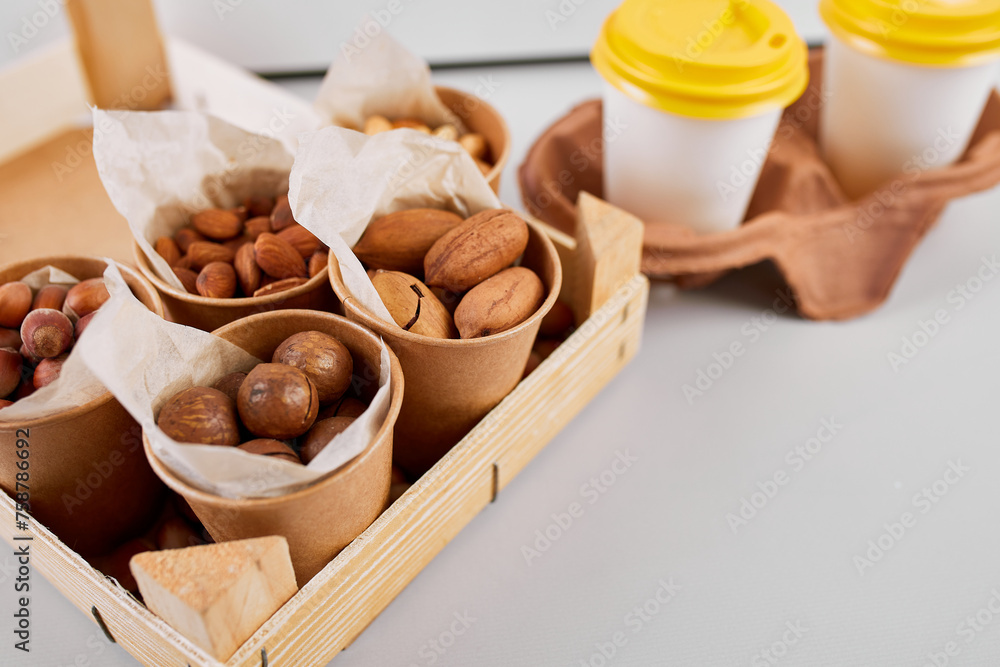 Two Takeaway Coffee Cups and a Variety of Nuts on a Bright Background.