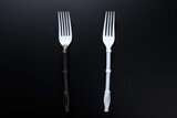 Artistic composition of a black and a white plastic fork on a dark background, symbolizing diversity and choice. Contrast Concept with Black and White Forks