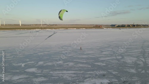 Aerial view of people snowkiting sport on frozen ice lake in winter, Netherlands