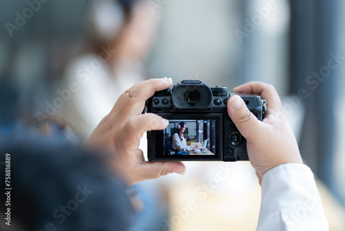 Close-up of hands holding a camera taking a picture of a person.