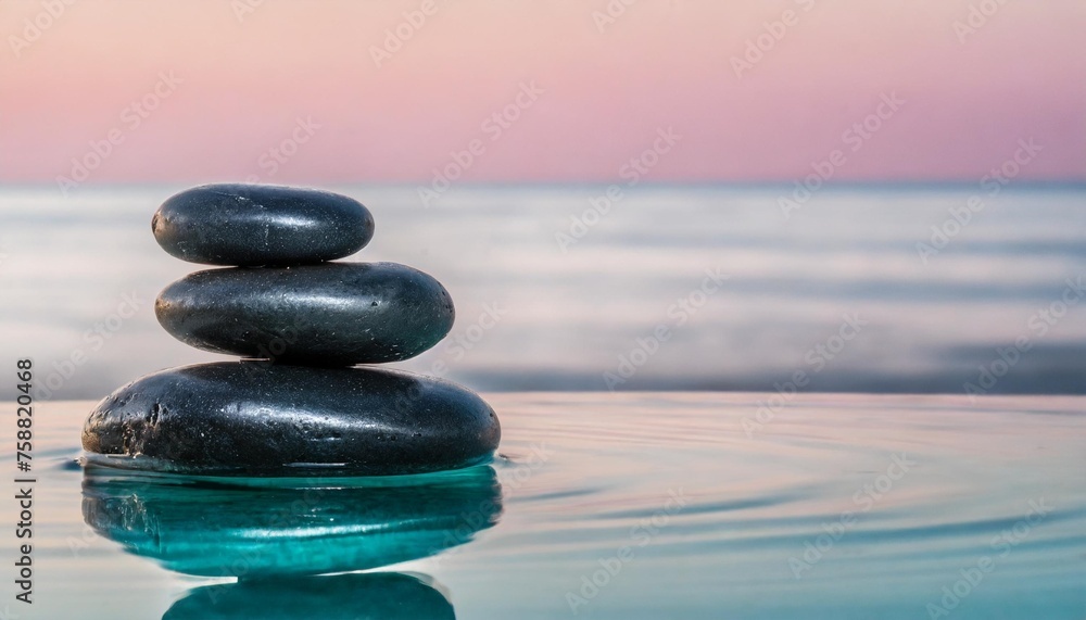 calm zen stones reflecting in turquoise water against the pink horizon with a blur background with copy space