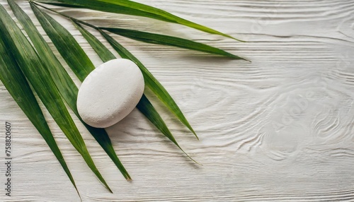 top view of natural white stones and palm leaves on a white background spa background top view a tropical summer background for luxury product placement