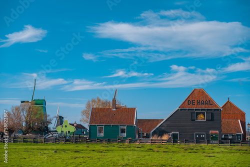 Traditional Dutch windmills in the rural landscape of Zaanse Schans village. Ancient houses brightly colored in spring season at sunset