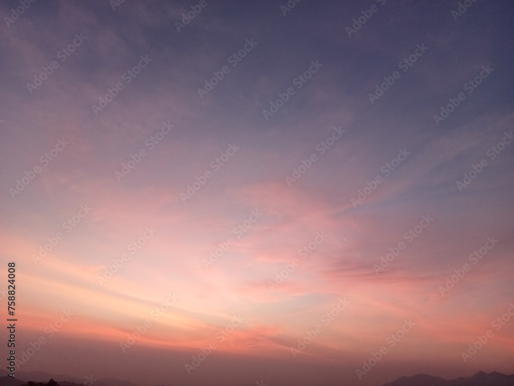 The sky has purple-orange tones in the early morning as the sun rises over the mountains