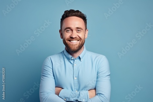 Portrait of a handsome smiling man with crossed arms against blue background